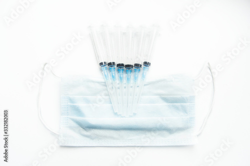 Syringes lying on a medical mask on a white background  top view.