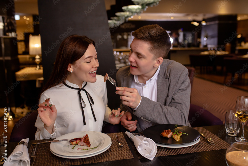 young man wants a woman to try this delicious food. attractive lady sit accepting courtship by her boyfriend. lovely couple in luxury restaurant