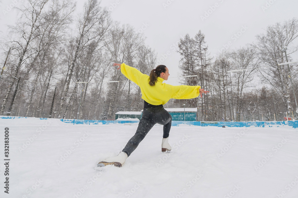 A young ice skater is training at an outdoor ice rink in December. A woman goes in for winter sports.