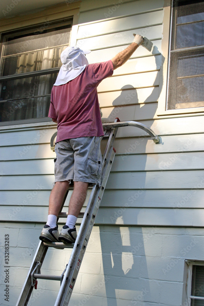 Man On Ladder Paints the Exterior of a House