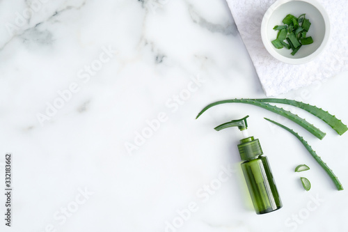 Natural organic SPA cosmetic product. Top view aloe vera gel and sliced plant leaves on marble background. Skincare, cosmetology, dermatology concept