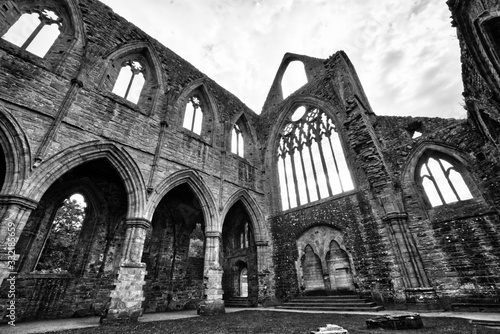 Black and white photo of The ruins of Tintern Abbey, founded by Walter de Clare, Lord of Chepstow, on 9 May 1131. It is situated adjacent to the village of Tintern in Monmouthshire, Wales, UK. photo