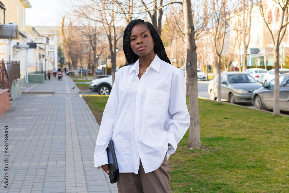 Close up portrait of a beautiful young african american woman with pigtails hairstyle in a business suit and white oversized blouse walks the street Close up portrait of a beautiful young african american woman with pigtails hairstyle in a business suit and white oversized blouse walks the street