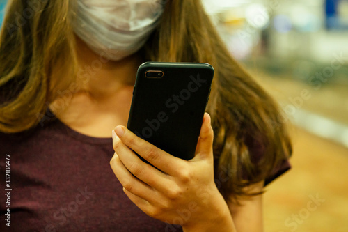foreign travel woman in mask holding phone in airport .Flight delay/flight cancellation airspace is closed because corona virus epidemic
