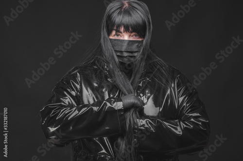 Female wearing protection face mask against coronavirus. Banner panorama woman preventive gear. Girl wearing gloves and latex coat protecting against covid. Black background and black mask