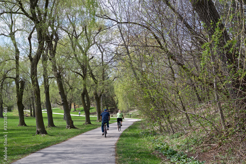 Happy couple riding bicycles in public park in early spring
