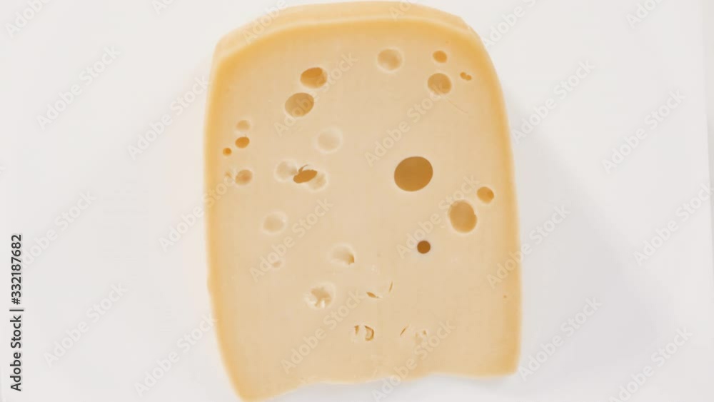 Flat lay. Large slice of semi soft part skim cheese on a white background. Flat lay. Large slice of semi soft part skim cheese on a white background.