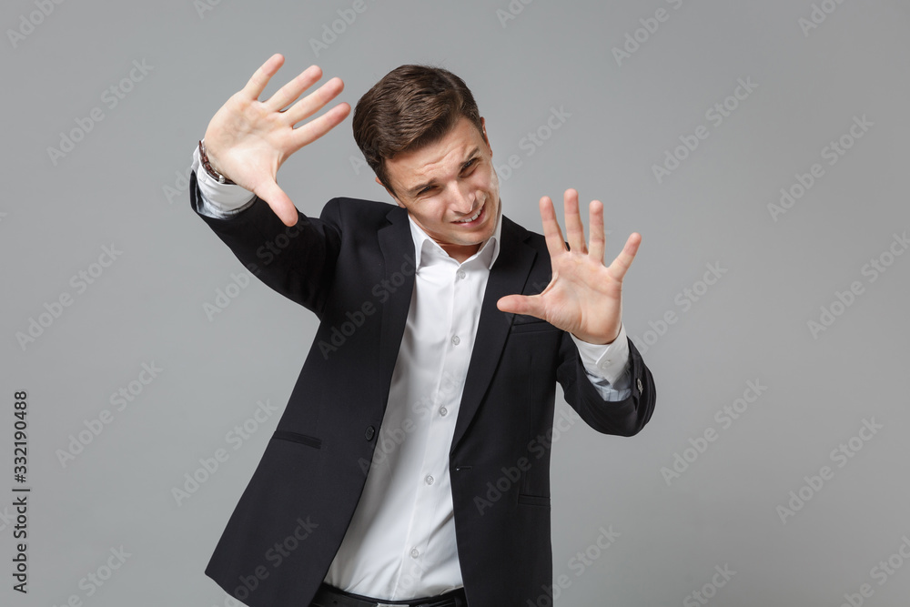 Displeased business man in classic black suit shirt isolated on grey background. Achievement career wealth business concept. Mock up copy space. Showing stop gesture with palms, covering with hands. Displeased business man in classic black suit shirt isolated on grey background. Achievement career wealth business concept. Mock up copy space. Showing stop gesture with palms, covering with hands.
