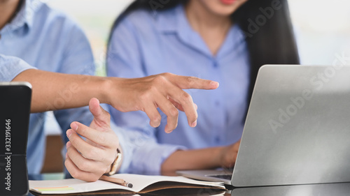 Cropped image of business developer team working together by using a computer tablet and laptop while sitting at the modern working desk over comfortable office as background.