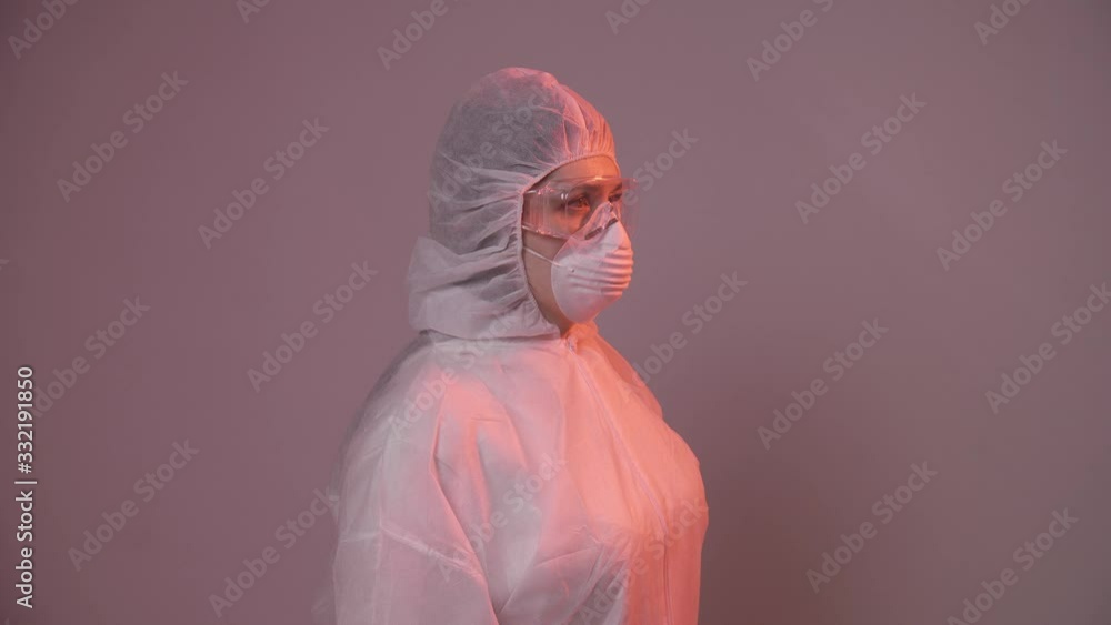 Professional female doctor in mask standing in hospital room putting glasses on. Health care concept. Laboratory employee Professional female doctor in mask standing in hospital room putting glasses on. Health care concept. Laboratory employee
