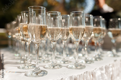 Elegant glasses with champagne standing in a row on serving table during party or celebration