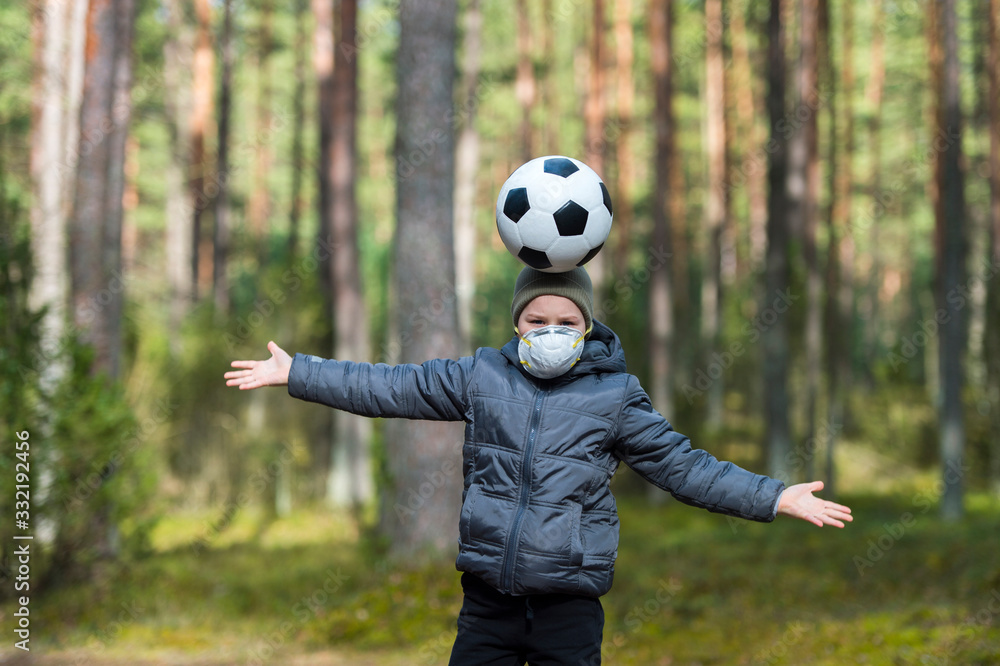 Little boy with a mask due to the corona virus play ball in the park. Coronavirus quarantine