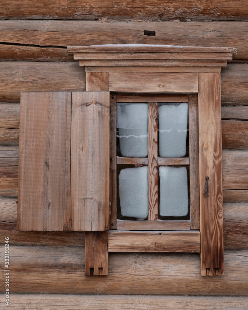 Traditional old houses made of wooden planks. Window with an asymmetric shutter . Traditional old houses made of wooden planks. Window with an asymmetric shutter .