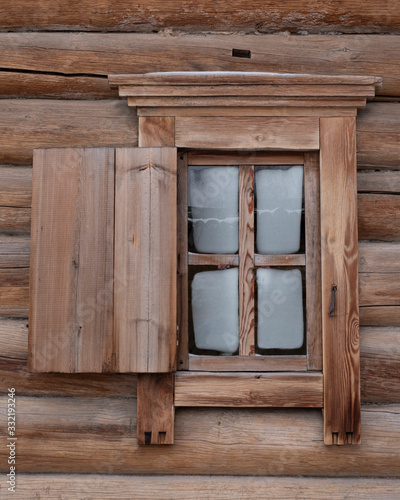 Traditional old houses made of wooden planks. Window with an asymmetric shutter .