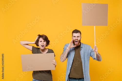 Canvas Print Displeased protesting young people hold protest signs broadsheet blank placard on stick scream with hands gesture isolated on yellow background