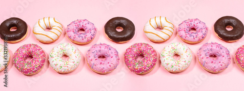 Doughnuts with multicolored glaze laid out in two rows on trendy pink background. Creative web banner.