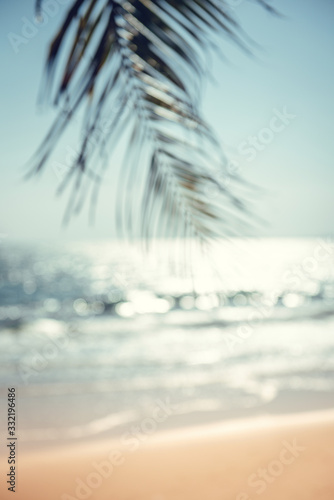 Blurred green palm leaf on tropical beach with bokeh sun light wave abstract background. Summer vacation and travel concept, Copy space