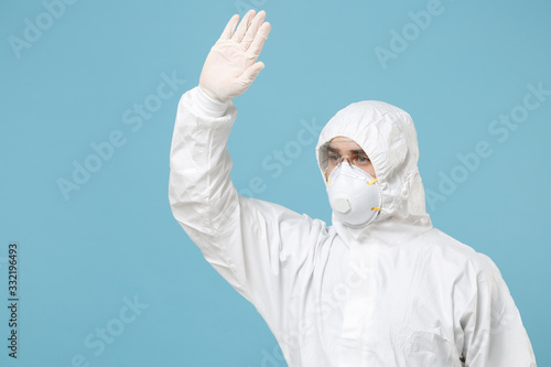 Man in white protective suit respirator mask isolated on blue background studio. Epidemic pandemic new rapidly spreading coronavirus 2019-ncov originating in Wuhan China, medicine flu virus concept.