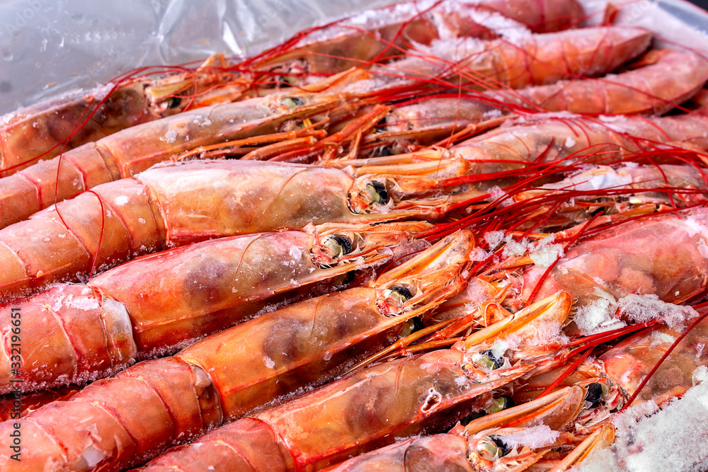 Amazing fresh large frozen shrimps. Pink fresh uncooked shrimps. Close-up. Delivery of frozen seafood to stores in package with hoarfrost on counter. Delicacies, sea food concept.