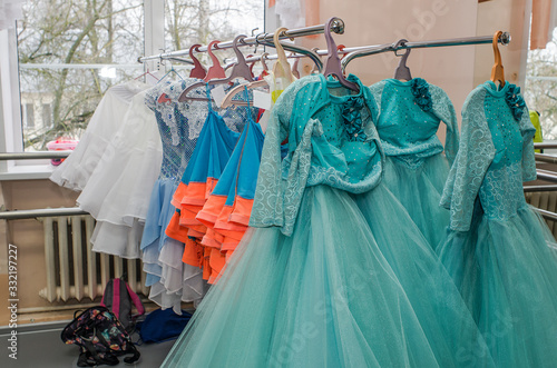 A row of stage costumes for upcoming performances by dance actors hangs on a floor hanger.