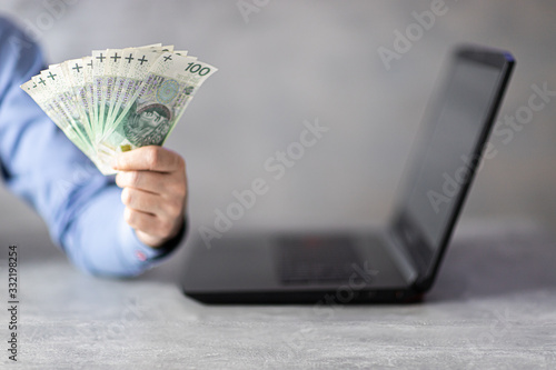 Bizmesmen trzymający gotówkę przy komputerze. Koncepcja zarabiania online