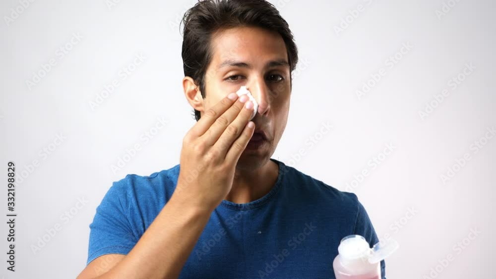 Handsome young Caucasian man put moisturizer lotion to cotton pad for cleaning beauty face, anti aging. Attractive guy use cleansing daily before apply moisturizer on his face. Skin care concept Handsome young Caucasian man put moisturizer lotion to cotton pad for cleaning beauty face, anti aging. Attractive guy use cleansing daily before apply moisturizer on his face. Skin care concept