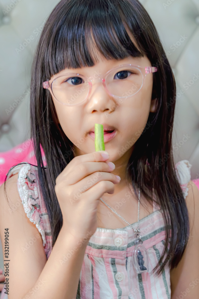 Portrait of cheerful asian girl eating salad with joy. She is looking aside with curiosity and smiling. Eating vegetables by child make them healthier Portrait of cheerful asian girl eating salad with joy. She is looking aside with curiosity and smiling. Eating vegetables by child make them healthier