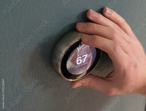 Foto Hand adjusting the dial on smart home thermostat