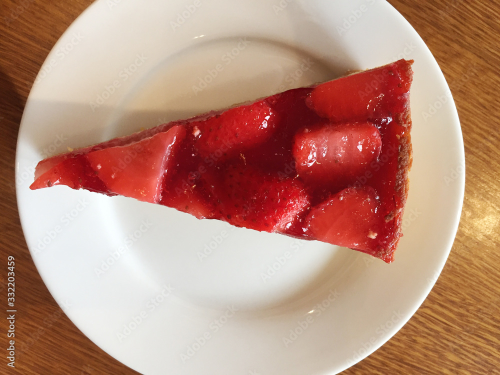 Slice of cheesecake with strawberries on a white plate.