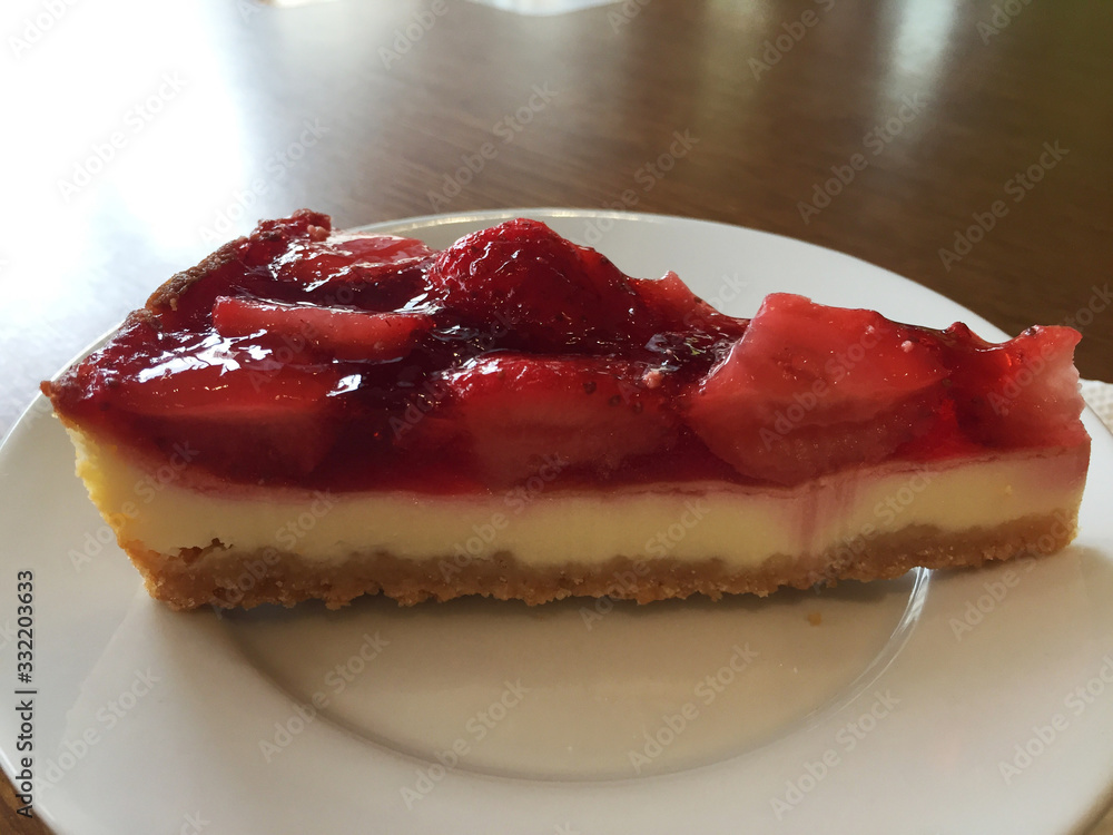 Slice of cheesecake with strawberries on a white plate.