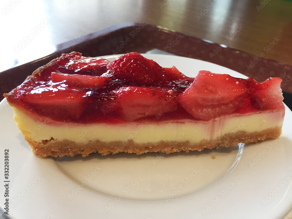Slice of cheesecake with strawberries on a white plate.