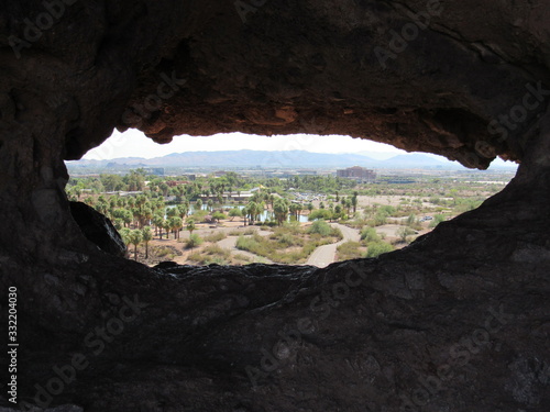 View through the Hole-in-the-Rock formation at Papago Park located in Phoenix and Tempe, Arizona with mountains and blue sky in the background 