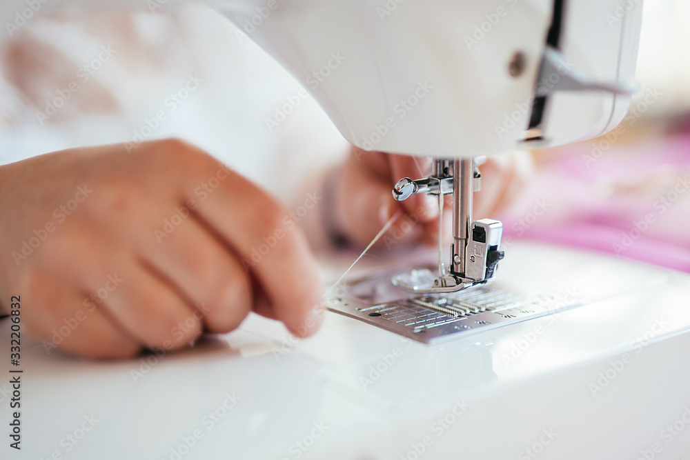 Seamstress puts a thread on a needle in a sewing machine