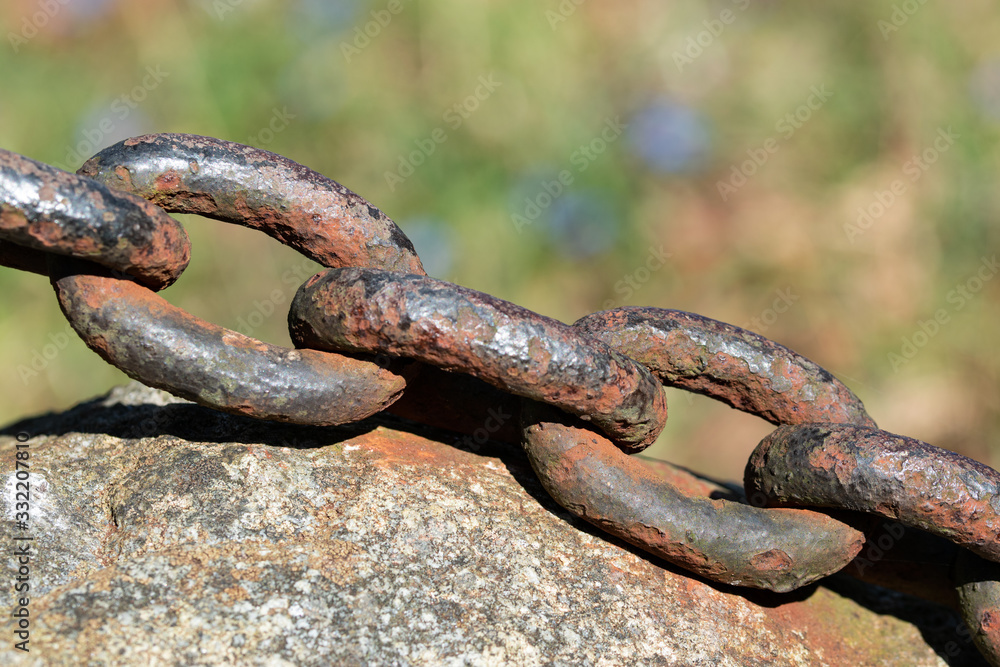 Old thick rusty chain of heavy iron close up, placed on a rock with blurred background Old thick rusty chain of heavy iron close up, placed on a rock with blurred background