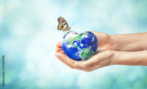 Fototapeta Naklejka Na Ścianę i Meble -  Together we can safe the world and offer the better world for our children and Earth day concept, Butterfly and love heart shaped earth on hands, Elements of this image furnished by NASA