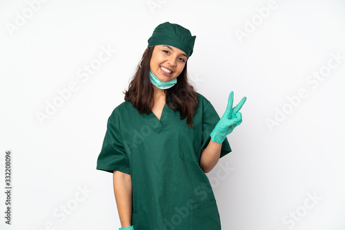Surgeon woman in green uniform isolated on white background smiling and showing victory sign