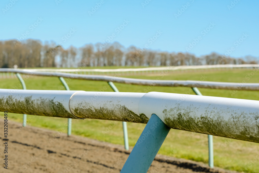 Shallow focus of a professional horse racing track shown the lightweight tubular fencing near an ascending curve. Used dayly by professional jockeys and trainers.