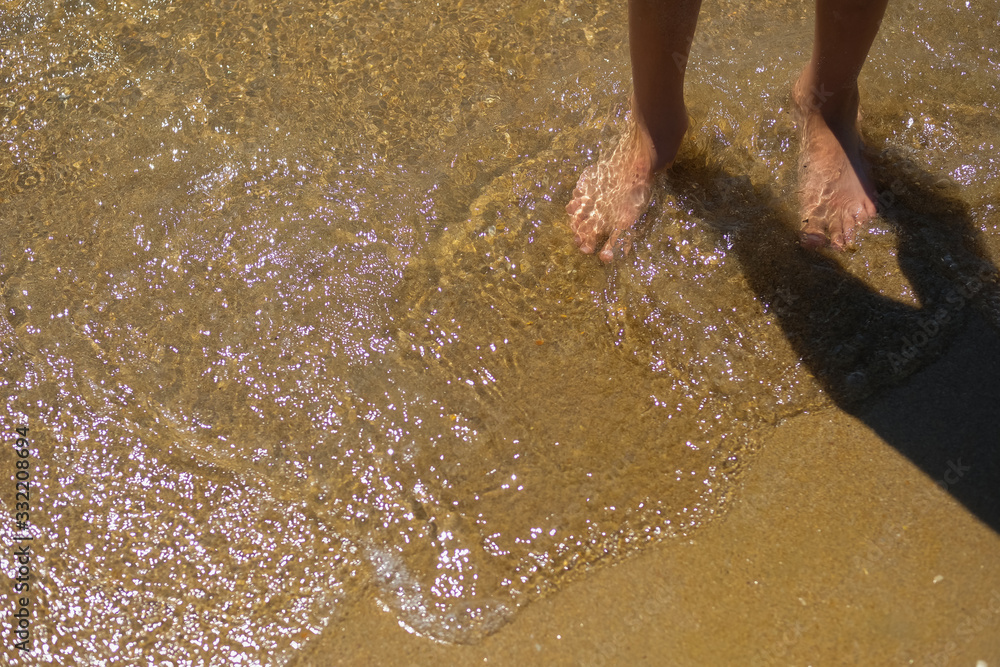 Young boy bare feet at the transparent sea waves with sand. Child on the beach. Young boy bare feet at the transparent sea waves with sand. Child on the beach.