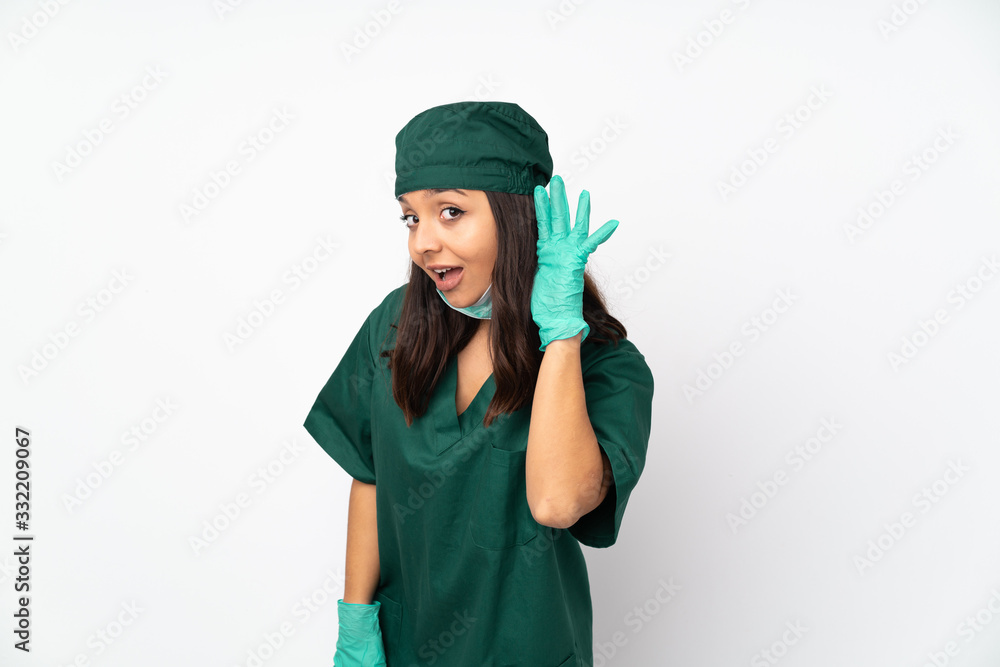 Surgeon woman in green uniform isolated on white background listening to something by putting hand on the ear Surgeon woman in green uniform isolated on white background listening to something by putting hand on the ear