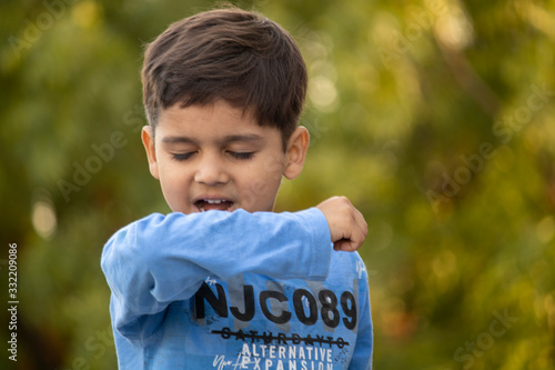 Indian child coughing on his elbow showing tips to protecting corona virus photo