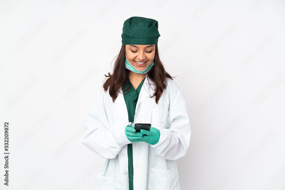 Surgeon woman in green uniform isolated on white background sending a message with the mobile Surgeon woman in green uniform isolated on white background sending a message with the mobile