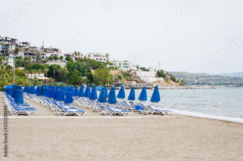 Rows of empty blue sun loungers and umbrellas on the beach. Camel Beach in Turkey.