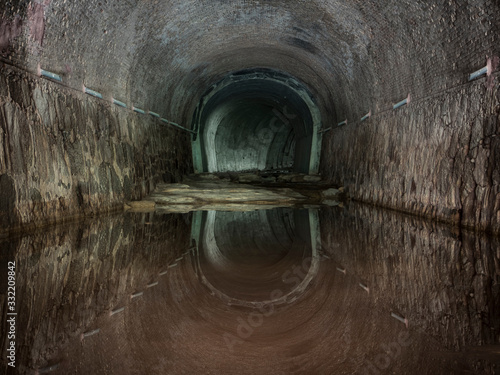 Túnel abandonado de desagüe de agua con reflejo del techo.