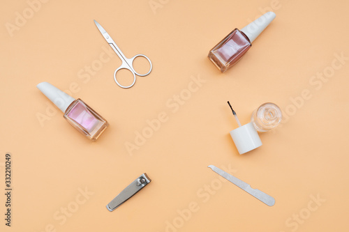 Set of manicure instruments and tools with nail polish on orange color background, top view
