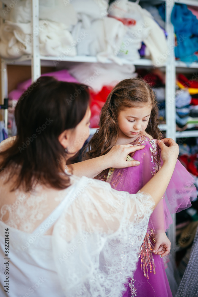Naklejka premium A seamstress ruler measures the parameters of a child. Little girl in the workshop