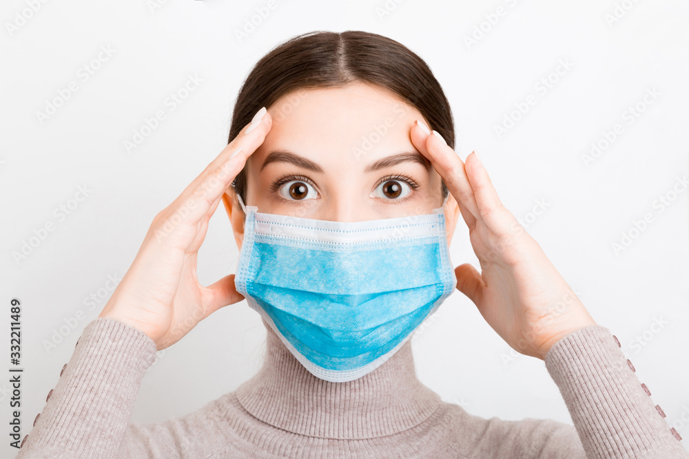 Portrait of young shocked woman wearing medical mask at white background. Protect your health. Coronavirus concept Portrait of young shocked woman wearing medical mask at white background. Protect your health. Coronavirus concept