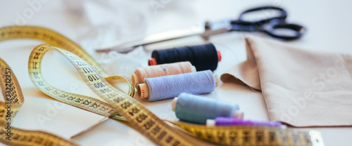 Composition of seamstress threads and scissors on a white table. Concept of a clothing designer photo