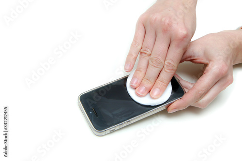 The detail of hands cleaning a mobile phone´s display with a tampon with disinfection. Protection against transfer of the viruses and diseases like corona virus. Isolated on a white background. 