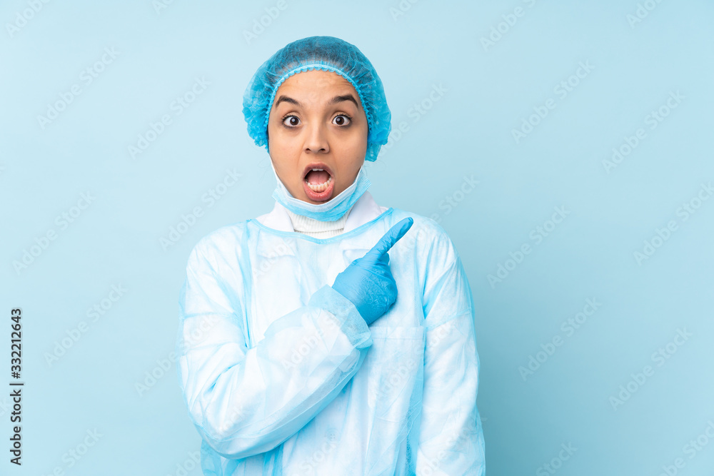 Young surgeon Indian woman in blue uniform surprised and pointing side Young surgeon Indian woman in blue uniform surprised and pointing side