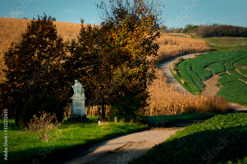 A roadside Catholic figurine standing by the road among Moravian fields